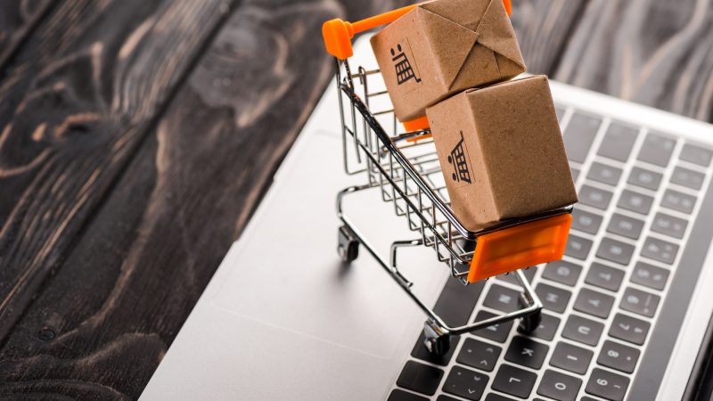 toy boxes in small shopping cart on laptop, e-commerce concept