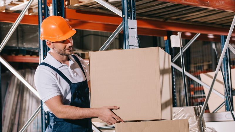 warehouse worker taking cardboard box from stack in warehouse